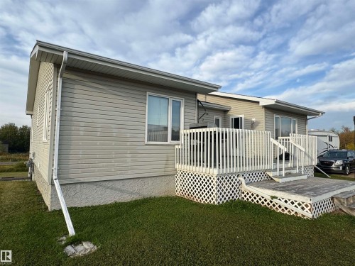 Exterior featuring horizontal siding, white trim windows, white deck with lattice skirting, and a gabled roofline - 20120 Twp Rd 515, Rural Beaver County, AB 