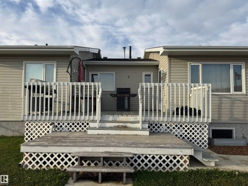 Multi-level wooden deck with lattice skirting, featuring white railings and dual-pane windows - 20120 Twp Rd 515, Rural Beaver County, AB 