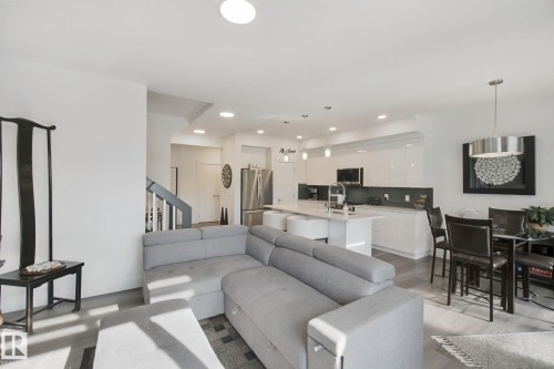 Open-concept living space featuring wood-finish flooring, recessed lighting, and a modern kitchen with a large island - 153 Cavanagh Common Sw, Edmonton, AB 