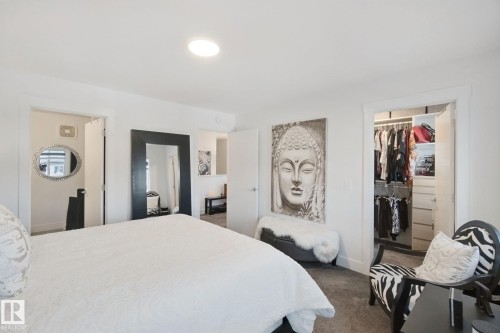 Spacious bedroom featuring neutral carpeting, recessed ceiling lighting, and multiple closet spaces with sliding door access - 153 Cavanagh Common Sw, Edmonton, AB 