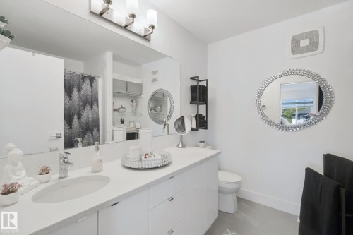 Dual vanity with undermount sinks, wall-mounted light fixture, large wall mirror, and built-in shelving - 153 Cavanagh Common Sw, Edmonton, AB 