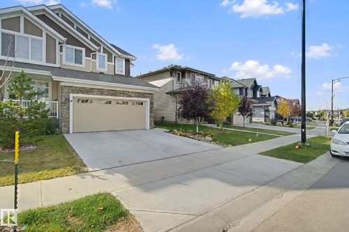 Two-story residence featuring a stone and siding exterior, an attached two-car garage, and a concrete driveway - 153 Cavanagh Common Sw, Edmonton, AB 
