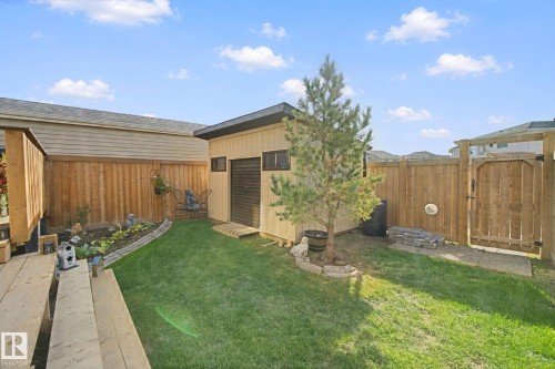 Manicured lawn, wood fencing, garden shed, patio gate, and planted garden bed - 153 Cavanagh Common Sw, Edmonton, AB 