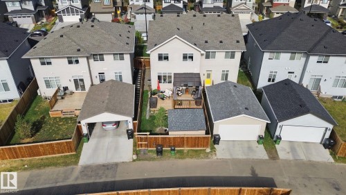 Rear exterior featuring a wood deck, manicured lawn, wood privacy fencing, and a detached carport - 153 Cavanagh Common Sw, Edmonton, AB 