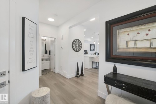 Light wood-finish flooring throughout, recessed lighting, and a white vanity with a rectangular basin sink - 153 Cavanagh Common Sw, Edmonton, AB 