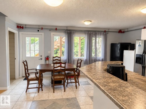Tile flooring with a diamond pattern, three windows with natural light, and a white paneled door - 18929 99A Avenue Nw, Edmonton, AB 