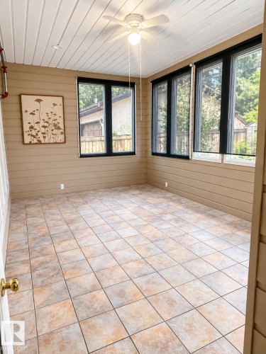 Room featuring tile flooring, multiple windows with dark frames, a ceiling fan, and horizontal paneling on the walls - 18929 99A Avenue Nw, Edmonton, AB 