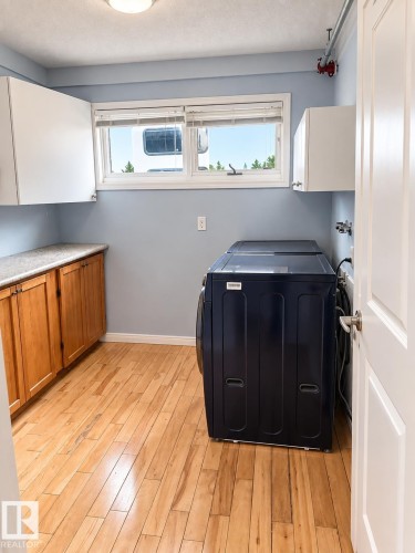Wood-finish flooring, white overhead cabinetry, and wood-finish lower cabinetry with a light-toned countertop - 18929 99A Avenue Nw, Edmonton, AB 