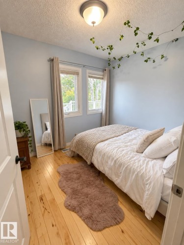 Hardwood flooring, light blue wall paint, double windows with window treatments, and a flush mount ceiling light - 18929 99A Avenue Nw, Edmonton, AB 