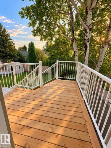 Expansive wood-plank deck with white metal railings, descending to a lower level with additional white metal railings - 18929 99A Avenue Nw, Edmonton, AB 