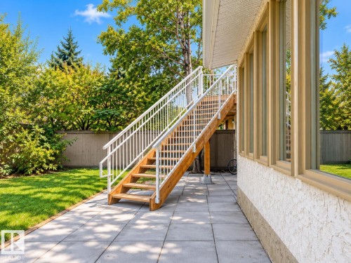 Paver patio with a wood staircase featuring white railings, stucco exterior, and multi-pane windows - 18929 99A Avenue Nw, Edmonton, AB 