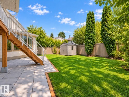 Expansive lawn area, concrete paver patio, wood staircase with white railings, and a storage shed - 18929 99A Avenue Nw, Edmonton, AB 