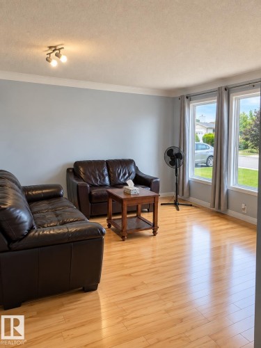 Light wood-finish flooring, multiple windows with neutral drapes, and a ceiling-mounted light fixture - 18929 99A Avenue Nw, Edmonton, AB 