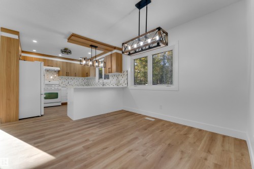 Open-concept kitchen and dining area featuring wood-finish flooring, white walls, and a window providing natural illumination - 52314 Rge Road 215, Rural Strathcona County, AB 