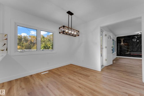 Expansive room featuring wood-finish flooring, white walls, and a multi-pane window - 52314 Rge Road 215, Rural Strathcona County, AB 