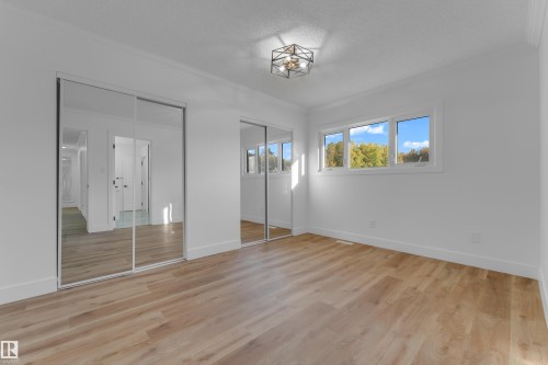 Wood-finish flooring, mirrored sliding closet doors, multiple windows, and a flush mount light fixture - 52314 Rge Road 215, Rural Strathcona County, AB 