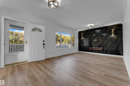 Wood-finish flooring, white walls, and a black stone fireplace wall with an electric insert - 52314 Rge Road 215, Rural Strathcona County, AB 