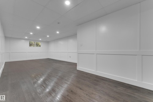 Spacious room featuring wood-finish flooring, white paneling, recessed lighting, and a window - 52314 Rge Road 215, Rural Strathcona County, AB 