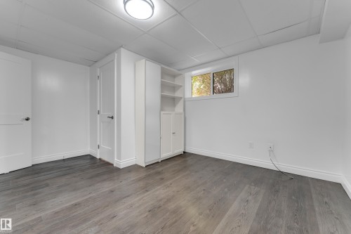Recessed ceiling with flush mount lighting, wood-finish flooring, built-in shelving, white trim, and a window - 52314 Rge Road 215, Rural Strathcona County, AB 