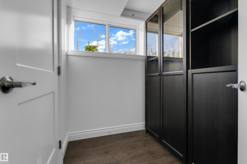 Built-in storage cabinetry with glass-paneled doors, wood-finish flooring, white trim, and a window providing natural light - 52314 Rge Road 215, Rural Strathcona County, AB 