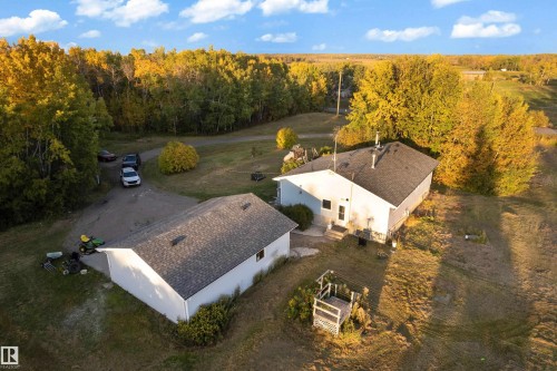 Spacious property featuring a main residence with a dark shingle roof, a detached ancillary building with a matching shingle roof, and a gravel driveway - 52314 Rge Road 215, Rural Strathcona County, AB 