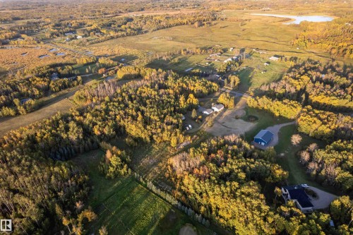 Expansive acreage featuring abundant mature trees, a private driveway, a detached garage, and a distant body of water - 52314 Rge Road 215, Rural Strathcona County, AB 