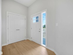 Entryway with wood-finish flooring, white walls, and a vaulted ceiling - 
