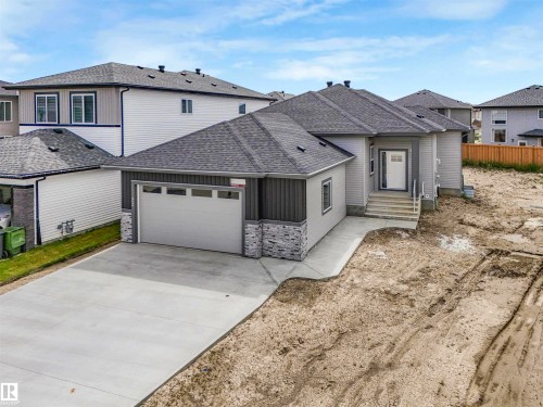 Modern exterior with gray siding, stone accents, and a covered entry - 22 Dalquist Bay, Leduc, AB 