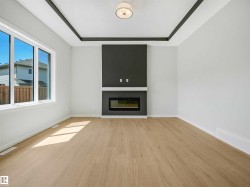 Recessed ceiling detail, wood-finish flooring, built-in electric fireplace, large windows, and a ceiling-mounted light fixture - 