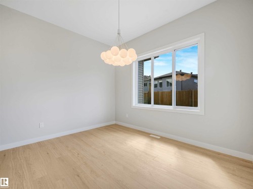 Wood-finish flooring with white trim, a large window, a contemporary chandelier, and light-colored walls - 22 Dalquist Bay, Leduc, AB 