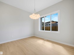 Wood-finish flooring with white trim, a large window, a contemporary chandelier, and light-colored walls - 