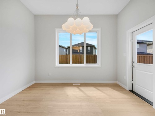 Light wood-finish flooring, white walls, and a contemporary chandelier - 22 Dalquist Bay, Leduc, AB 