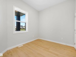 Light wood-finish flooring, neutral wall tones, and a single window with white trim - 