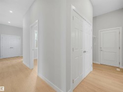 Wood-finish flooring throughout, bright white walls, recessed ceiling lighting, and panel interior doors - 