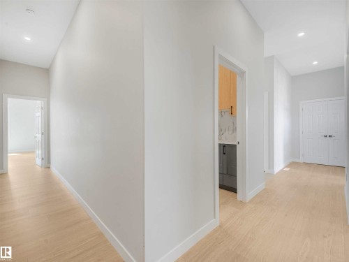 Light wood-finish flooring, recessed ceiling lighting, light gray wall finishes, and a paneled interior door - 22 Dalquist Bay, Leduc, AB 
