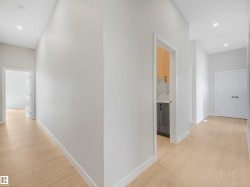 Light wood-finish flooring, recessed ceiling lighting, light gray wall finishes, and a paneled interior door - 