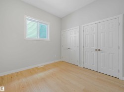 Light wood-finish flooring complemented by white walls, a white-framed window with horizontal blinds, and two sets of white paneled bifold doors - 
