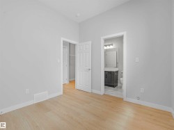 Light wood-finish flooring, white trim, and a gray vanity with a single basin sink - 