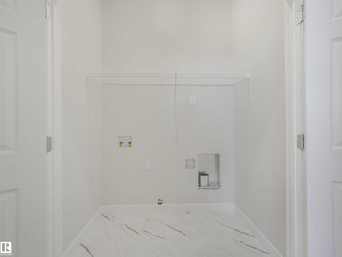 White tile flooring, laundry hookups, and wire shelving - 22 Dalquist Bay, Leduc, AB 