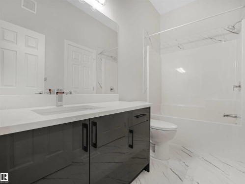 Vanity with a polished countertop and integrated sink, chrome faucet, and gray cabinetry - 22 Dalquist Bay, Leduc, AB 