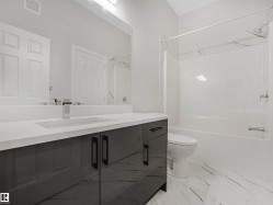 Vanity with a polished countertop and integrated sink, chrome faucet, and gray cabinetry - 