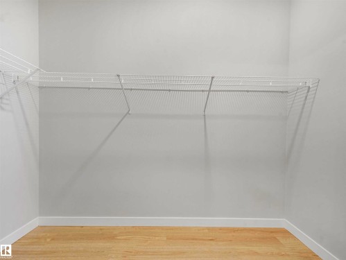 White wire shelving system installed in a corner, light wood-finish flooring, and white baseboards - 22 Dalquist Bay, Leduc, AB 