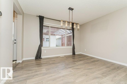 Wood-finish flooring, neutral wall tones, and a linear chandelier - 3203 Carpenter Landing Sw, Edmonton, AB 
