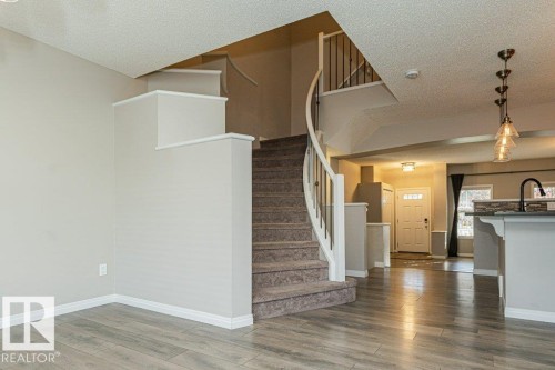 Curved staircase with metal spindles and carpeted treads - 3203 Carpenter Landing Sw, Edmonton, AB 