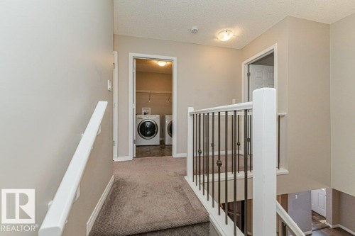 Laundry area with front-loading appliances, neutral wall paint, and carpeted flooring - 3203 Carpenter Landing Sw, Edmonton, AB 