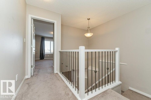 Carpeted hallway with a white spindle railing and a built-in ceiling light fixture - 3203 Carpenter Landing Sw, Edmonton, AB 