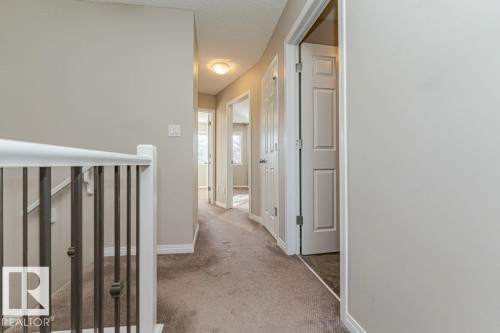 Hallway with neutral wall paint, carpet flooring, and white trim - 3203 Carpenter Landing Sw, Edmonton, AB 