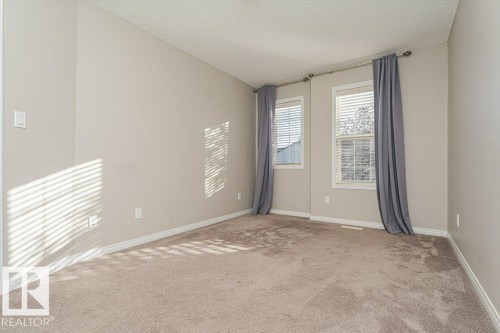 Soft-hued walls complementing carpeted flooring, featuring two windows with blinds - 3203 Carpenter Landing Sw, Edmonton, AB 
