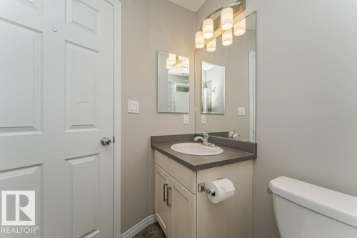 Single vanity with an integrated sink, dark countertop, and brushed nickel faucet - 3203 Carpenter Landing Sw, Edmonton, AB 