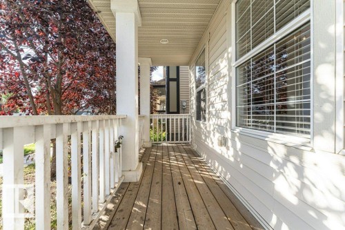 Covered porch featuring wood-finish flooring, white railing, and exterior wall with horizontal siding - 3203 Carpenter Landing Sw, Edmonton, AB 